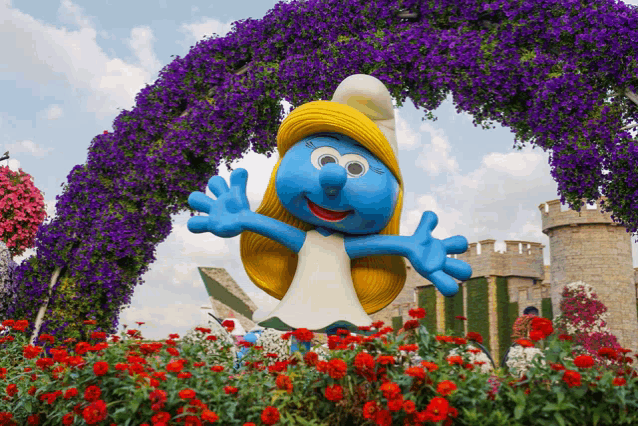 a smurf statue is surrounded by flowers and a castle