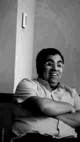 a black and white photo of a man with glasses smiling
