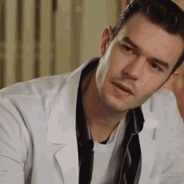 a close up of a man wearing a white coat