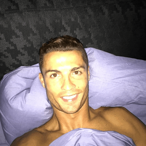 a shirtless man is laying in bed with a purple comforter