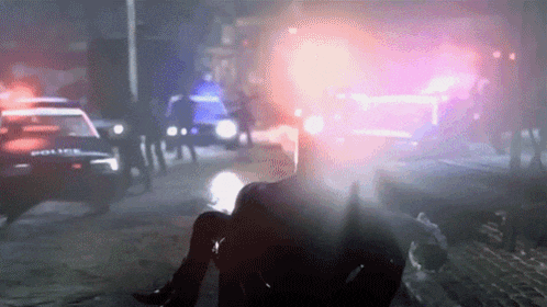 a police car is driving down a street with a man laying on the ground