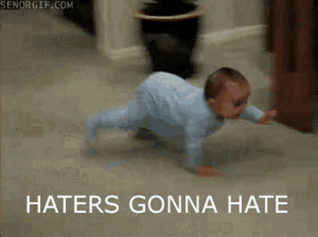 a baby is crawling on the floor with the words haters gonna hate above him