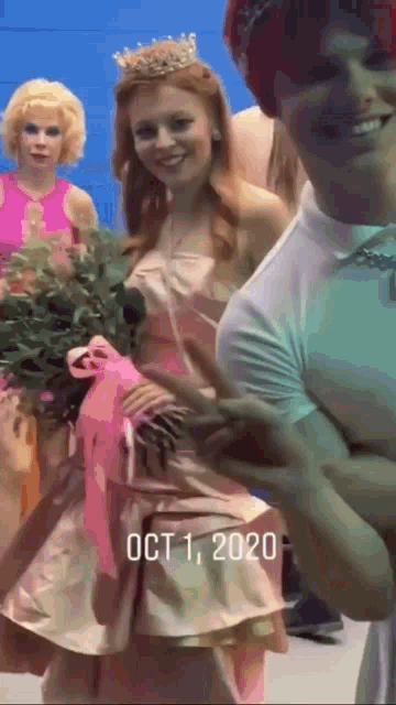 a woman in a pink dress with a crown on her head is holding a bouquet of flowers