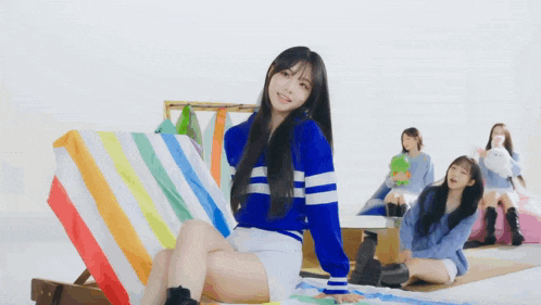 a girl in a blue and white striped sweater holds a white square in front of her face