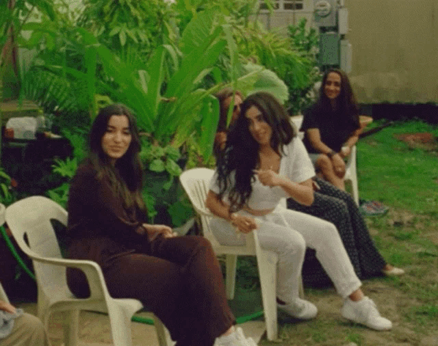 a group of women are sitting in chairs outside