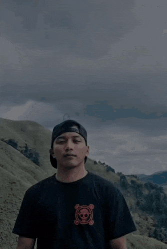 a man in a black shirt with a skull and crossbones on it stands in front of a lightning strike