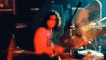 a blurry image of a person playing drums in a dark room