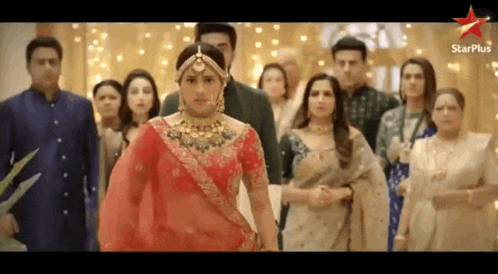 a bride in a red dress is standing in front of a group of people .