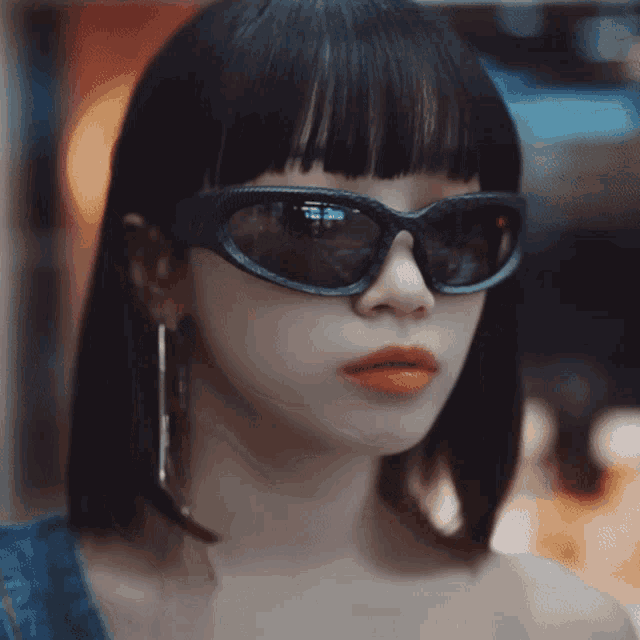 a close up of a woman wearing sunglasses and orange lipstick