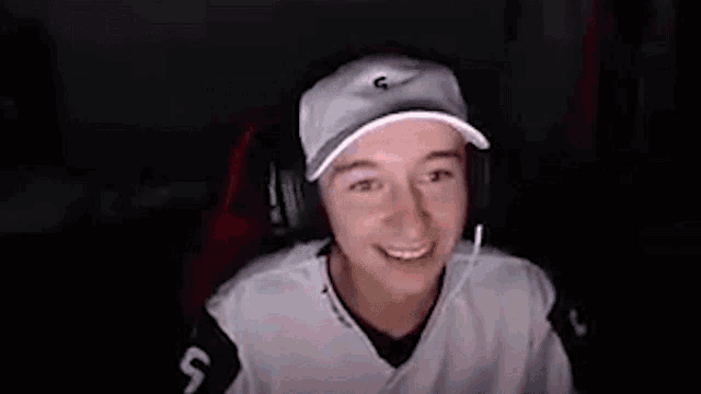 a young boy wearing a hat and headphones is sitting in front of a computer screen .
