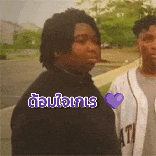 a man in a black shirt has a purple heart in front of his chest that says ' i love you ' in thai