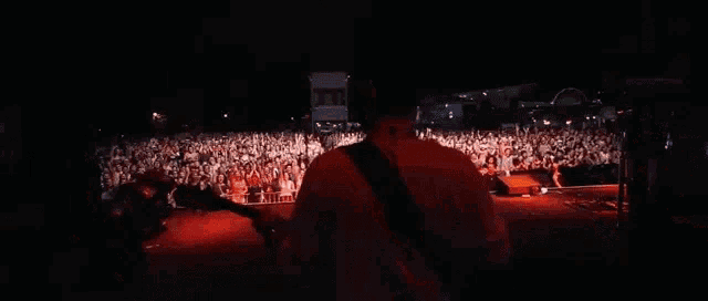 a man is playing a guitar in front of a crowd at a concert