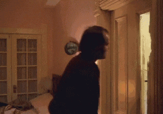 a man is standing in a bedroom with a clock on the wall
