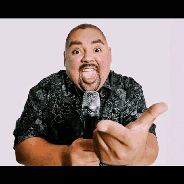 a man in a black shirt is holding a microphone and making a funny face