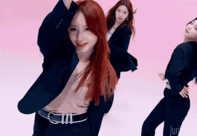 a woman with red hair is dancing in front of a pink background that says juri