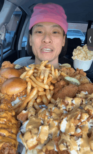 a man wearing a pink hat is eating a huge amount of food