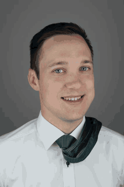 a man wearing a white shirt and a green tie is smiling