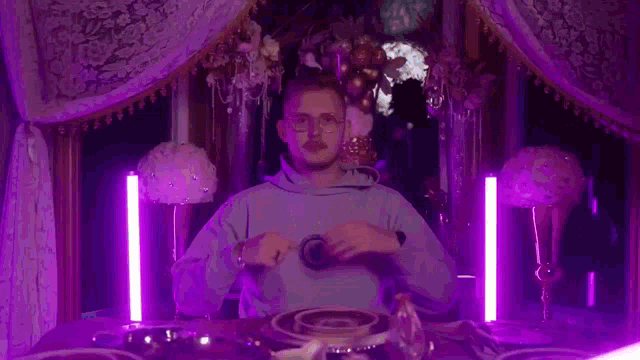 a man is sitting at a table in a room with purple lights .