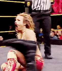 a woman in a wrestling ring with a referee wearing a shirt that says ' wwe '