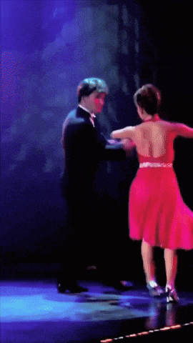 a man in a tuxedo and a woman in a red dress are dancing