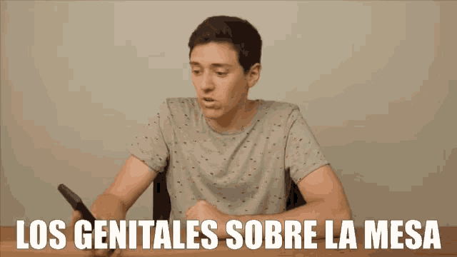a man sitting at a table with the words los genitales sobre la mesa on the bottom