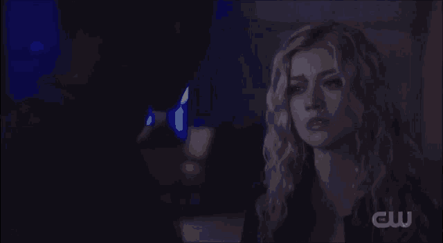 a man and a woman are looking at each other in a dark room with a cw logo in the corner .