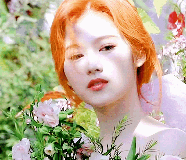 a woman with orange hair is holding a bouquet of flowers