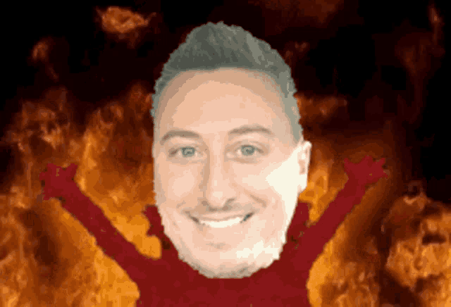 a man with his arms outstretched is smiling in front of flames