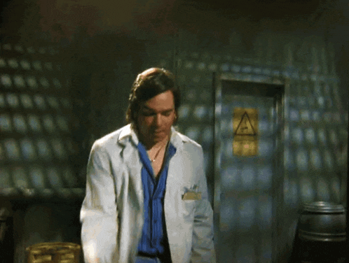 a man in a lab coat is pointing at something in front of a sign that says a