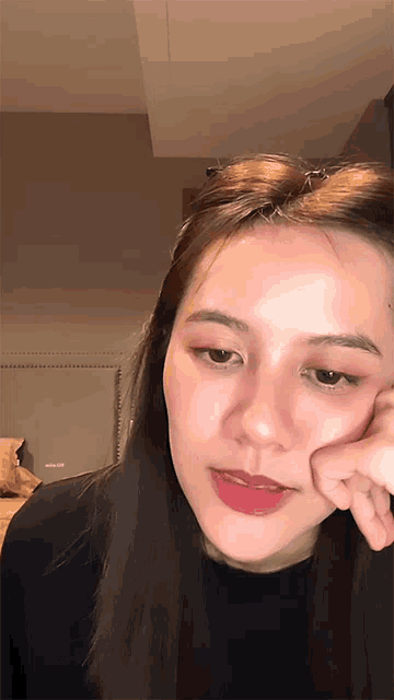 a close up of a woman 's face with a hand on her chin
