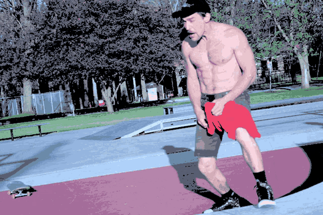 a man without a shirt is standing on a ramp holding a red shirt