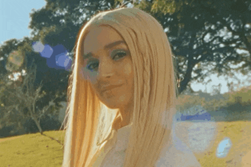 a woman with long blonde hair is smiling in a field