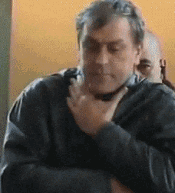 a man in a black jacket holds his hand to his mouth