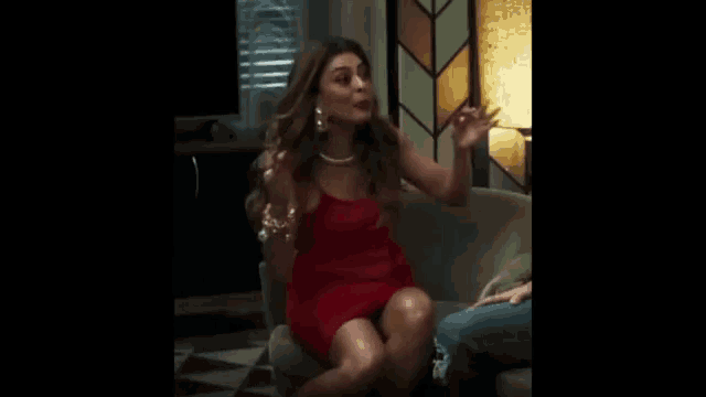 a woman in a red dress is sitting on a green couch