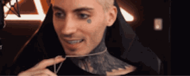a man with a tattoo on his face is smiling while sitting in a chair .