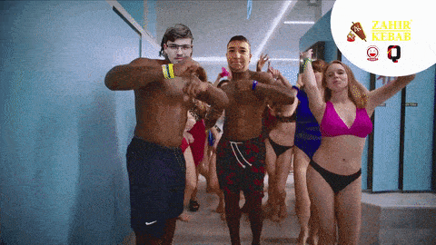 a group of people in swimsuits are dancing in a hallway with a sign that says zahir kebab