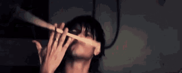 a man is playing a flute in a dark room with a mask on his face .