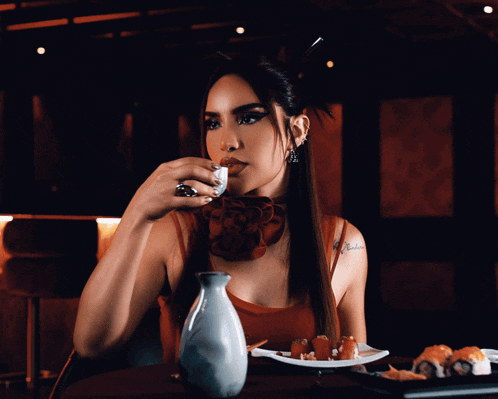 a woman sitting at a table with a plate of food and a bottle of alcohol