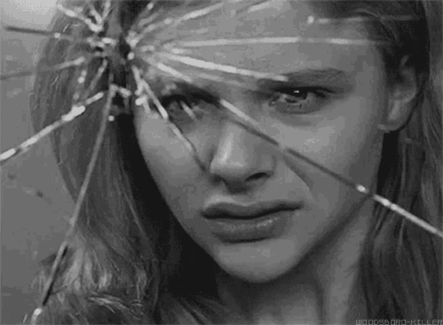 a woman 's face is visible through a broken mirror .