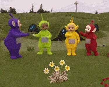 a group of teletubbies standing next to each other on a grassy field .