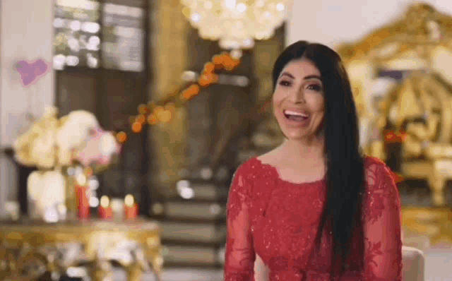 a woman in a red dress is sitting in a chair and laughing in a living room .