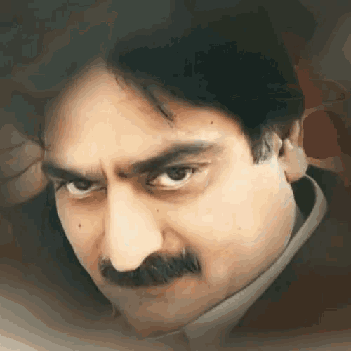 a man with a mustache looks at the camera with an angry look on his face