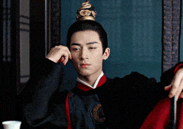 a man with a crown on his head is wearing a black and red outfit