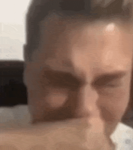 a man is covering his mouth with his hand while looking at the camera .