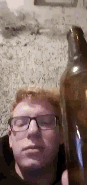 a man with glasses is holding a bottle of beer .