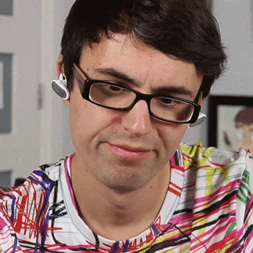 a man wearing glasses and ear buds looks at the camera