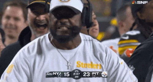a man wearing a steelers shirt is laughing while watching a football game