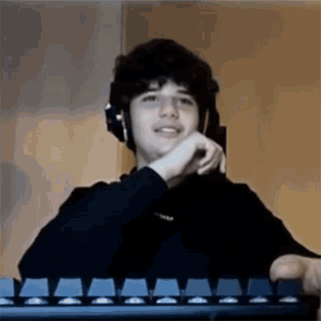 a young man wearing headphones is sitting in front of a computer keyboard .