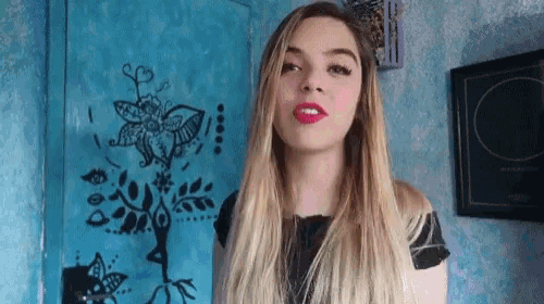 a woman with red lipstick stands in front of a blue wall with a butterfly on it