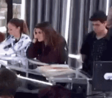 a group of people are sitting at a table in front of a computer screen .